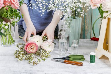 Woman arranging a bouquet with roses, matthiolas, ranunculus flo
