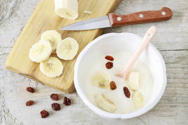 Sliced banana and a bowl of porridge with raisins. — Stock Photo, Image