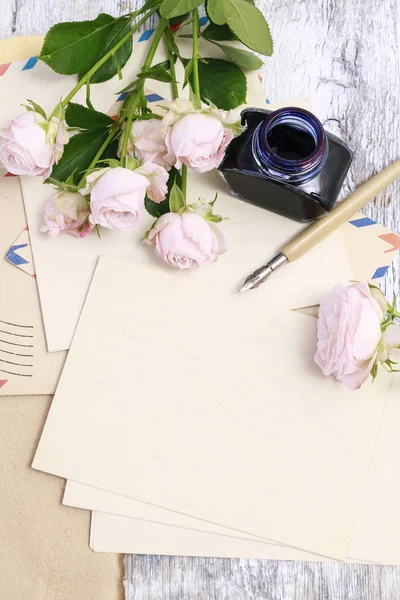 Starobylé psací potřeby a růžové růže kolem — Stock fotografie