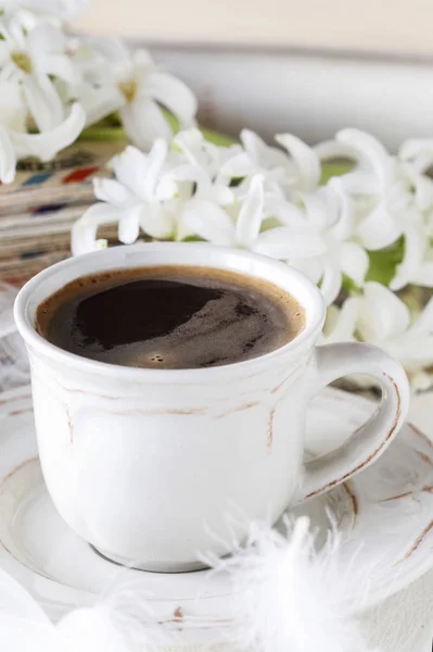 Kopp kaffe, hyacint blommor och vita fjädrar. — Stockfoto