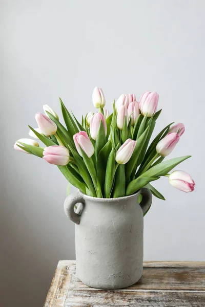 Strauß rosa Tulpen in grauer Keramikvase. — Stockfoto