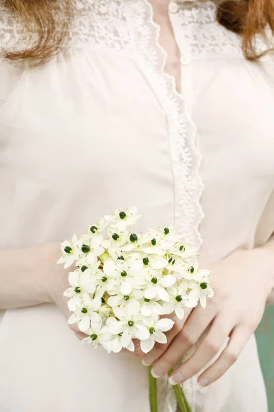 Woman holding bouquet of tiny white flowers