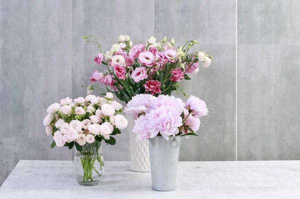 Rosas, peónias e lisianthus (eustoma) sobre fundo cinzento da parede — Fotografia de Stock