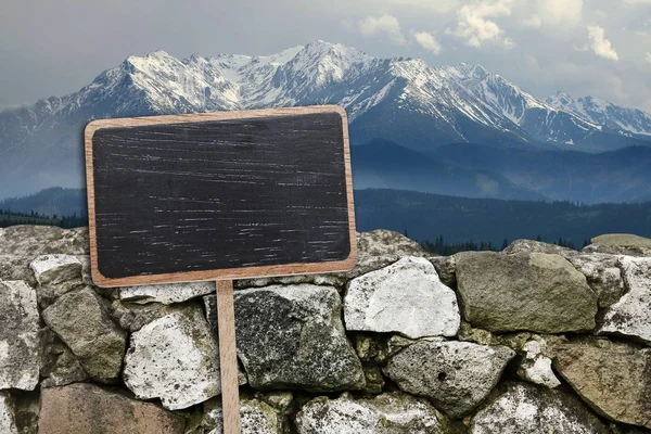 Blank blackboard label and stone wall