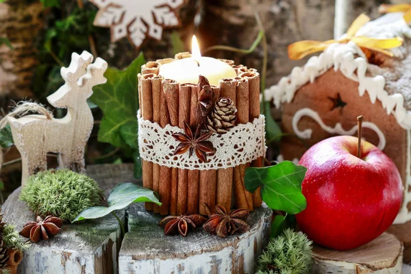 用肉桂棒、苔、常春藤叶和木材装饰的蜡烛 — 图库照片