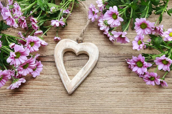 Corazón de madera entre flores de margarita . —  Fotos de Stock