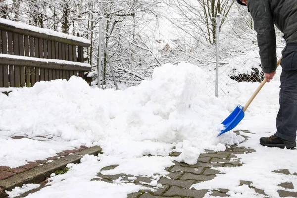 Человек убирает снег с тротуара после метели . — стоковое фото