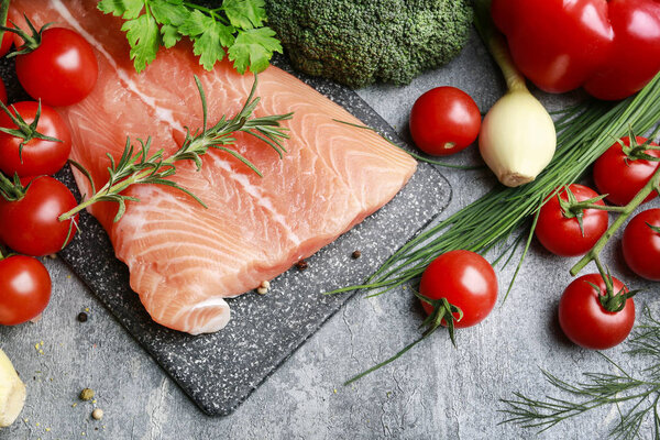 Raw fishes and vegetables on stone background