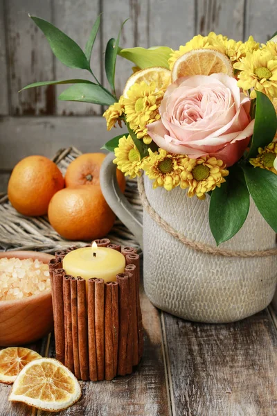 Свеча, украшенная коричными палочками и букет цветов . — стоковое фото