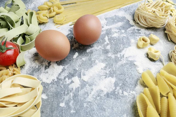 Mixed types and shapes of italian pasta on grey stone, backgroun — Stock Photo, Image