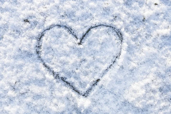 Heart handwritten on snow. Love symbol in winter.