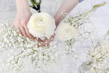Ranunculus çiçekleri ve beyaz gypso ile süslemeyapan kadın
