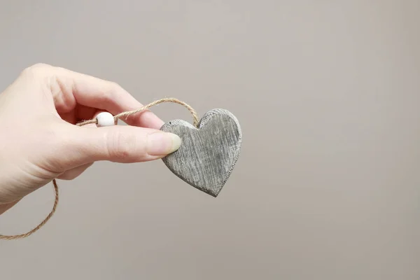 Femme tenant le coeur gris en bois dans sa main — Photo