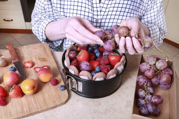 Vrouw bereidt Franse Charlotte cake met zomer fruit in huis — Stockfoto