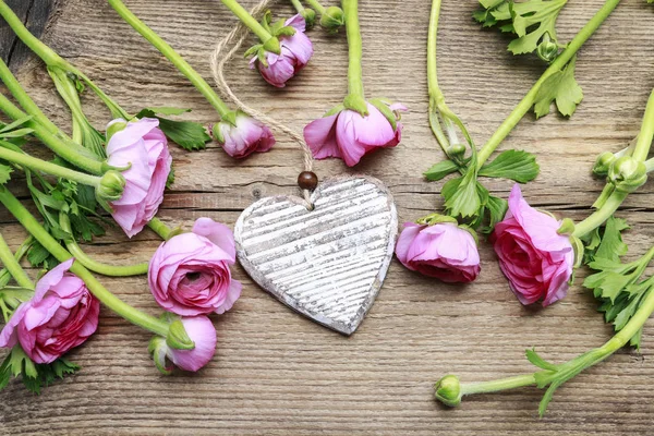 Corazón de madera y flores de buttercup persas rosadas — Foto de Stock