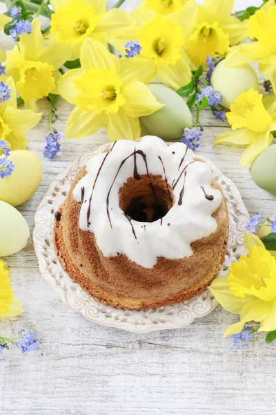 Traditional easter cake and bouquet of daffodils in the backgrou