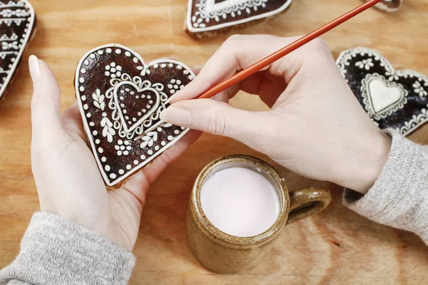 Donna decorazione biscotti di pan di zenzero a forma di cuore . — Foto Stock