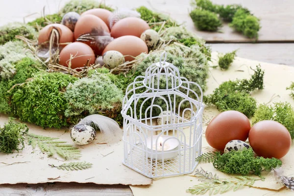 Vintage bird cage with candle, moss and Easter eggs around.