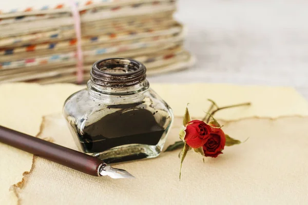 Tintenfass, Stift und getrocknete Rosen auf Vintage-Papier Hintergrund. Liebe l — Stockfoto