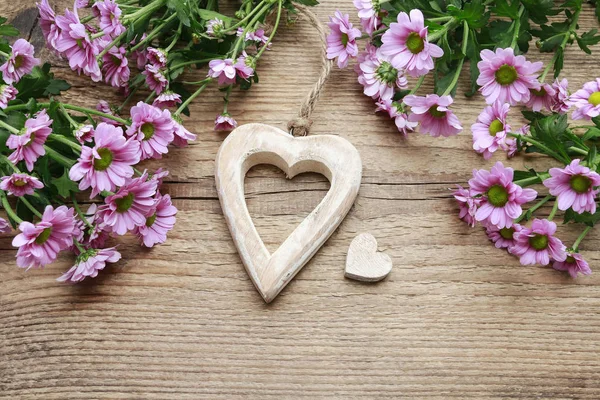 Corazones de madera entre flores de crisantemo rosa —  Fotos de Stock