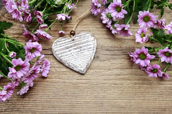 Corazones de madera entre flores de crisantemo rosa —  Fotos de Stock