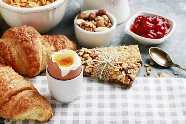 Frühstückszeit: weich gekochtes Ei, französische Croissants, Müsliriegel, — Stockfoto