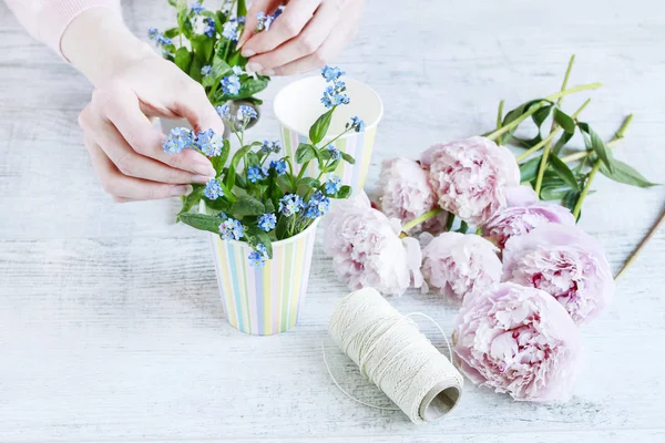 Donna che organizza mazzi di fiori con peonie e fiori forget-me-not — Foto Stock
