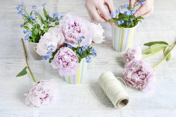 Frau arrangiert Sträuße mit Pfingstrosen und Vergissmeinnicht-Blumen — Stockfoto