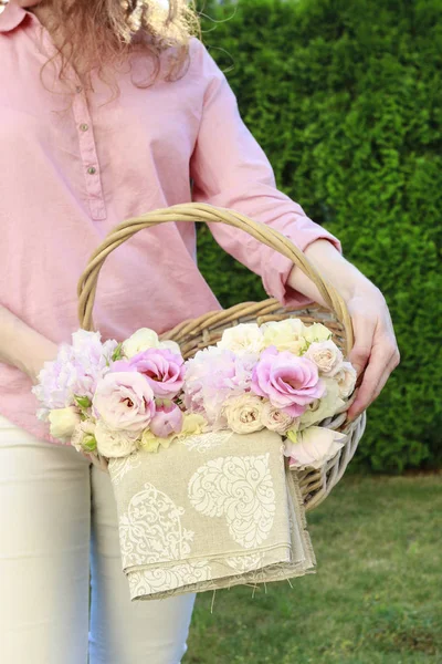 Mujer sosteniendo una cesta con flores rosas de verano . — Foto de Stock