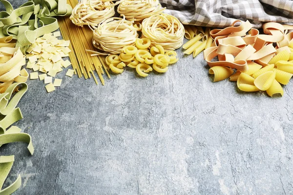 Gemischte Arten und Formen italienischer Pasta auf grauem Stein, Hintergrund — Stockfoto