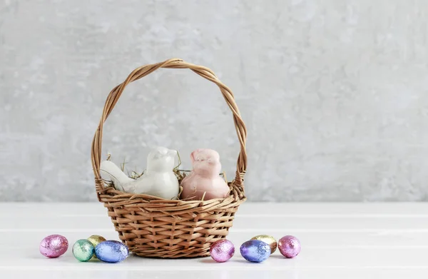 Two ceramic birds in wicker Easter basket. Eggs around, grey sto — Stock Photo, Image