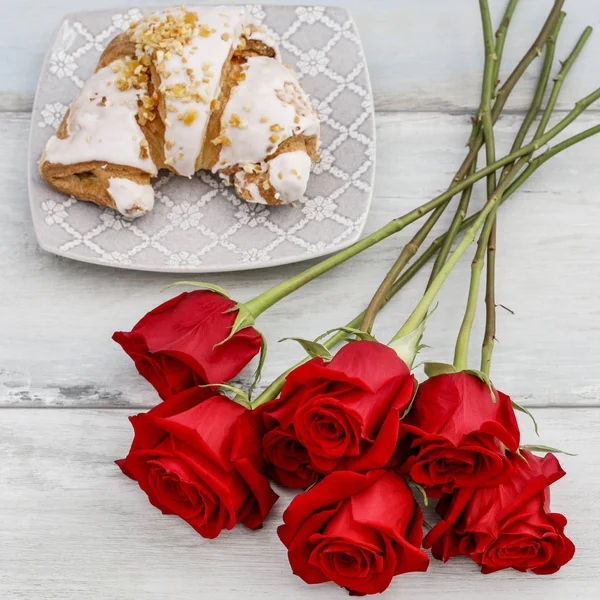 Franska croissand och bukett röda rosor. — Stockfoto