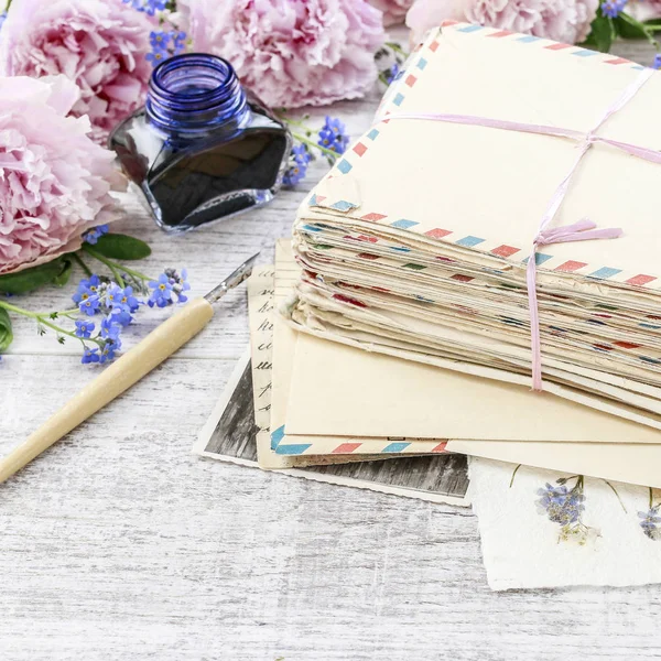 Empilement de lettres d'amour vintage et pivoines roses en arrière-plan — Photo