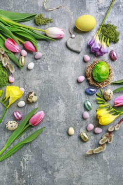 Renkli çiçekler ve gri, taş backgrou üzerinde paskalya yumurtaları boyalı