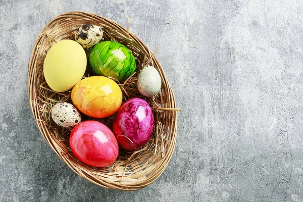 Basket of colorful Easter eggs on grey, stone background. — Stock Photo, Image