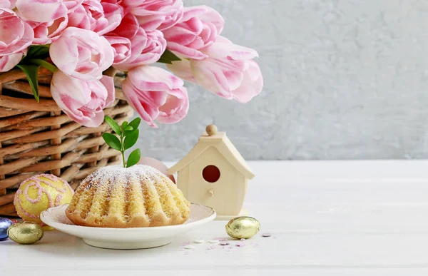 Gâteau de Pâques traditionnel et panier avec des tulipes roses dans le dos — Photo
