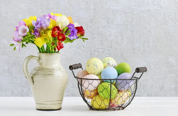 Bouquet of colorful freesia flowers and wire basket with Easter — Stock Photo, Image