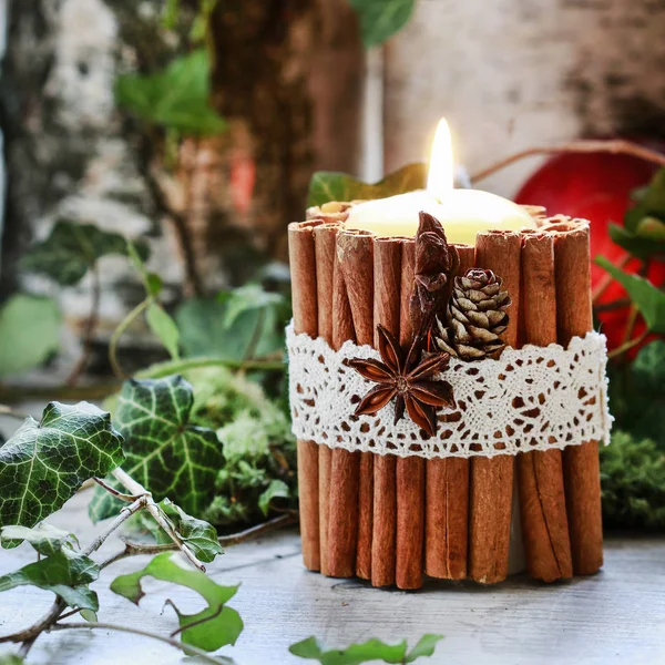 Candle decorated with cinnamon sticks, moss, ivy leaves and wood — Stock Photo, Image