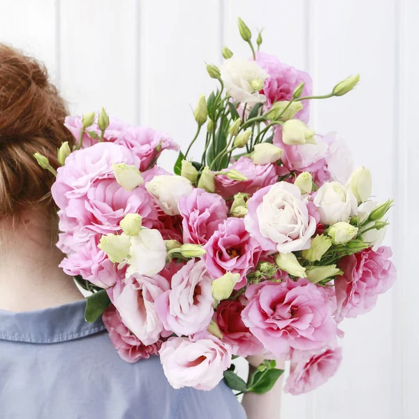 Nő virágárus kezében egy nagy rakás rózsaszín eustoma virágok. — Stock Fotó