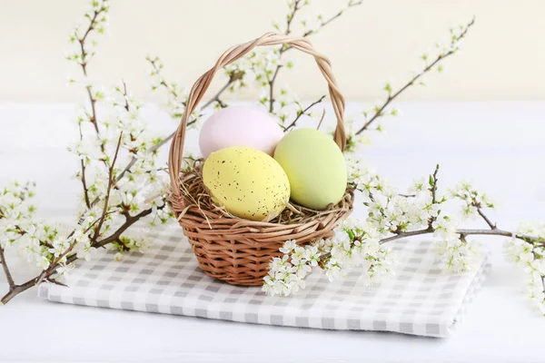 Basket with Easter eggs on hay and blooming cherry twigs. — Stock Photo, Image