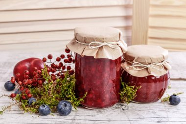 Kırmızı reçelli cam kavanozlar. Sonbahar meyveleri etrafında. 