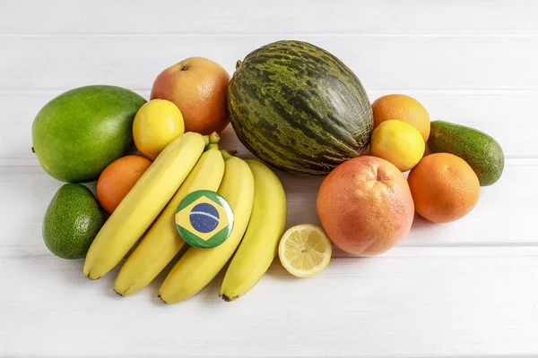Стопка бананов, апельсинов и манго на белом деревянном столе . — стоковое фото