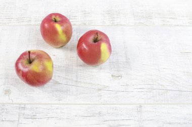 Beyaz tahta masada kırmızı elmalar.