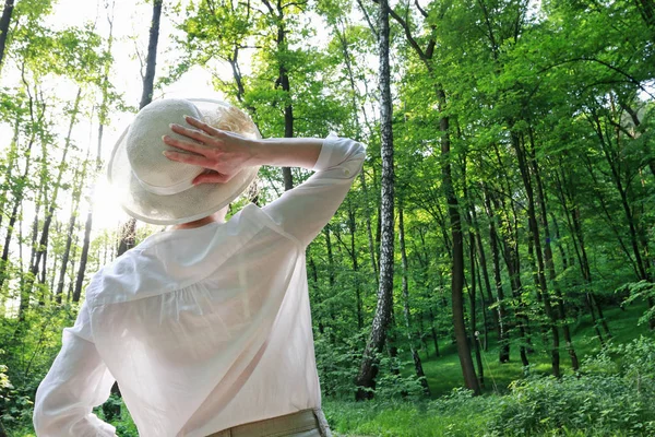 Jonge vrouw in Victoriaanse hoed kijken naar de hoge bomen in diepe f — Stockfoto