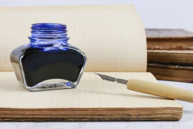 Mürekkep kuyusu, kalem ve eski bir defter. 