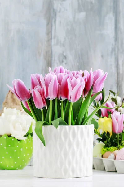 Tulipanes rosados en jarrón de cerámica blanca, fondo de madera azul . —  Fotos de Stock