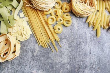 Gri taş arka planda İtalyan makarnasının karışık türleri ve şekilleri