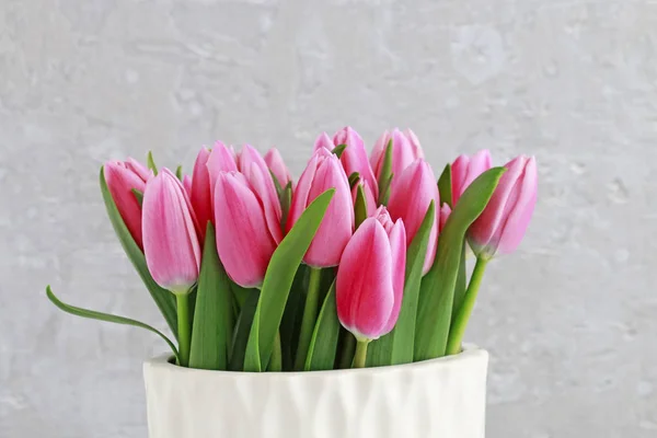 Tulipas cor-de-rosa em vaso de cerâmica branca, fundo de pedra cinza . — Fotografia de Stock