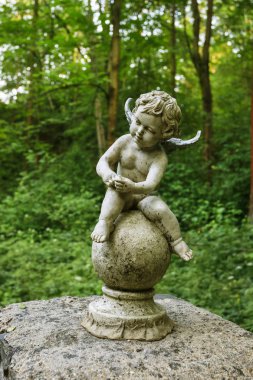 Bahçede taştan yapılmış bebek melek veya cupid figürü.