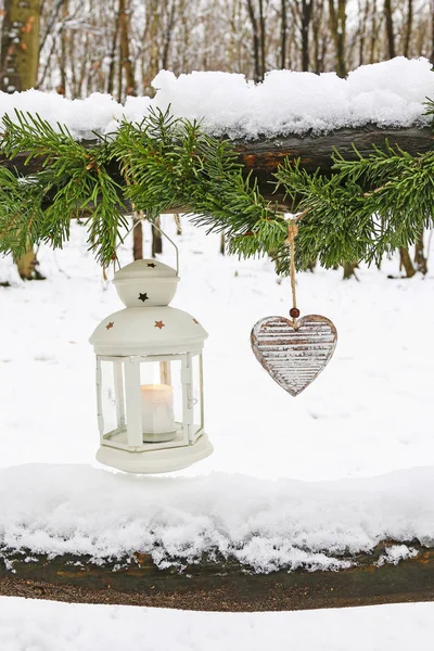 Fir garland, iron lantern and wooden hearts hanging in garden. — Stock Photo, Image